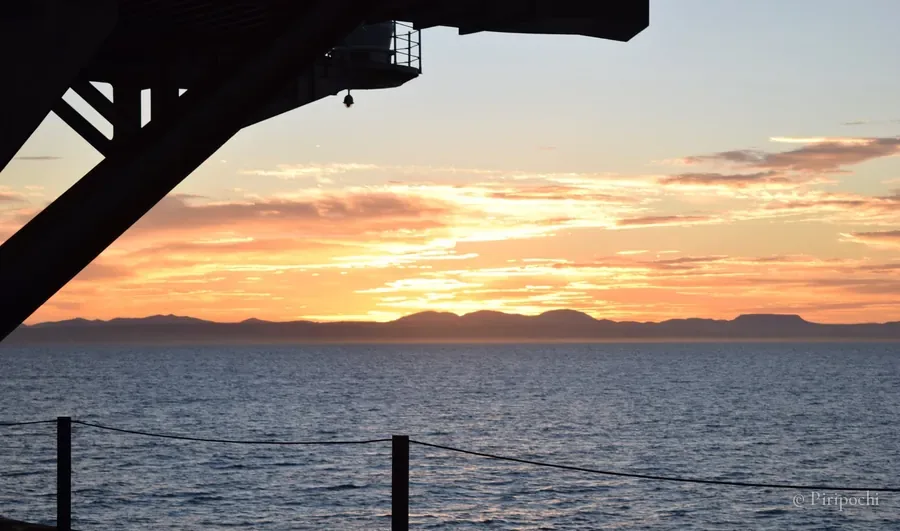 Atardecer anaranjado sobre el mar visto desde la cubierta de un barco